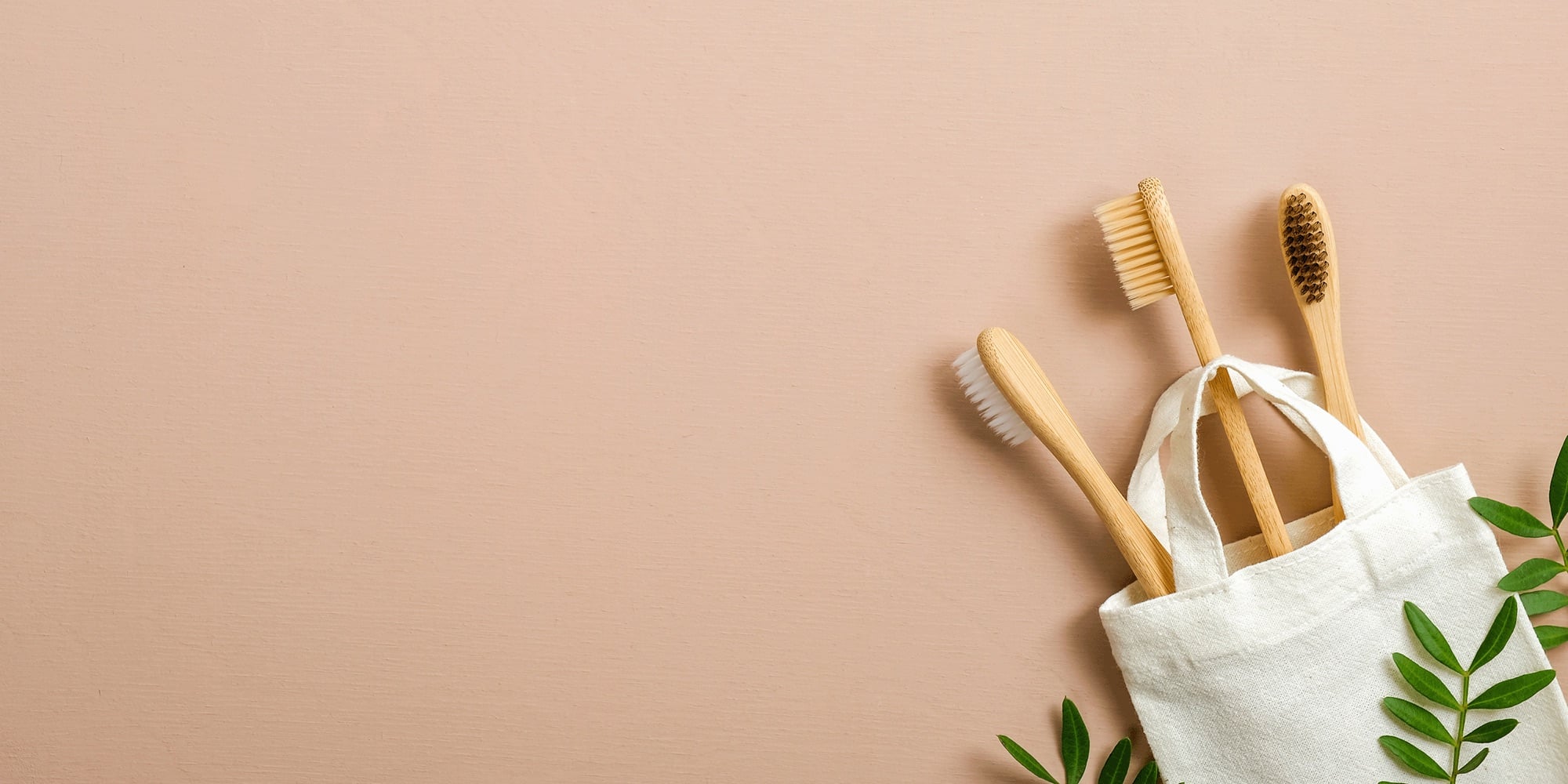 Bamboo toothbrushes in a cotton pouch on a warm background